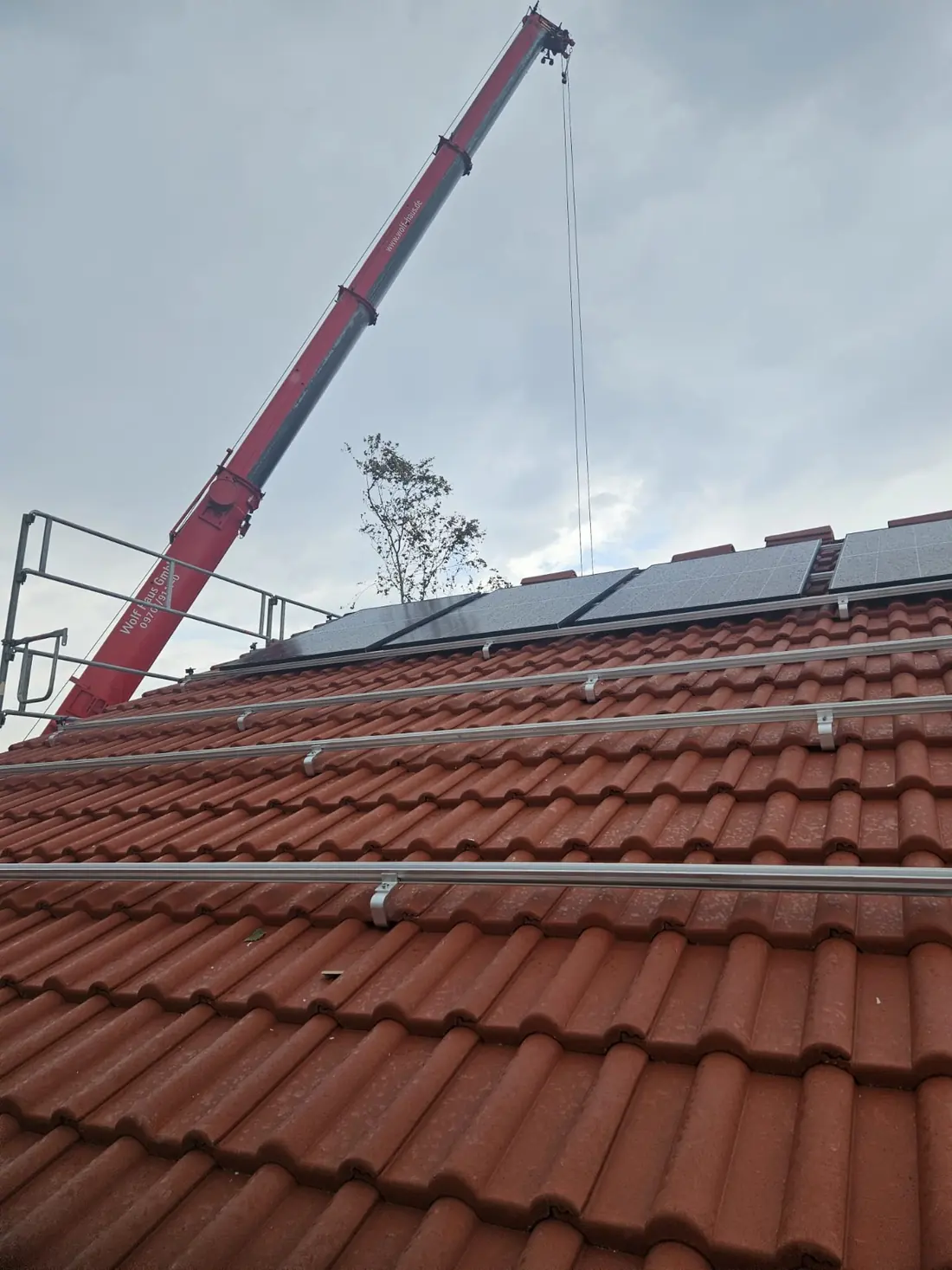 Kran hebt Photovoltaikmodule während der Montage auf das Dach